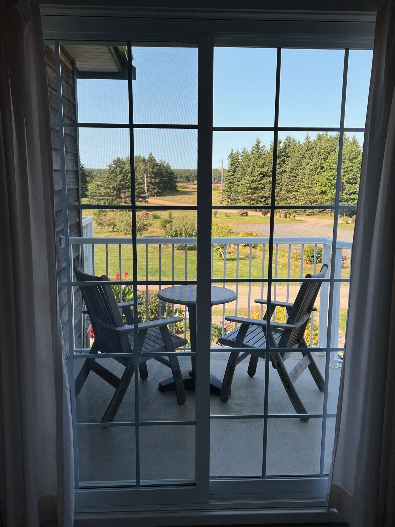 Blick aus einem Fenster auf eine Terrasse mit zwei Stühlen und einem Tisch.