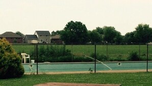 A picnic table in a grassy area with a fenced pool in the background. - Town N Country Motor Inn (Leamington)