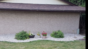 A building with a brick exterior, a number '200' sign, and a gravel pathway with potted plants. - Town N Country Motor Inn (Leamington)