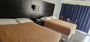 A hotel room with two beds, a nightstand, a lamp, a chair, and a table with a curtain. - Town N Country Motor Inn (Leamington)