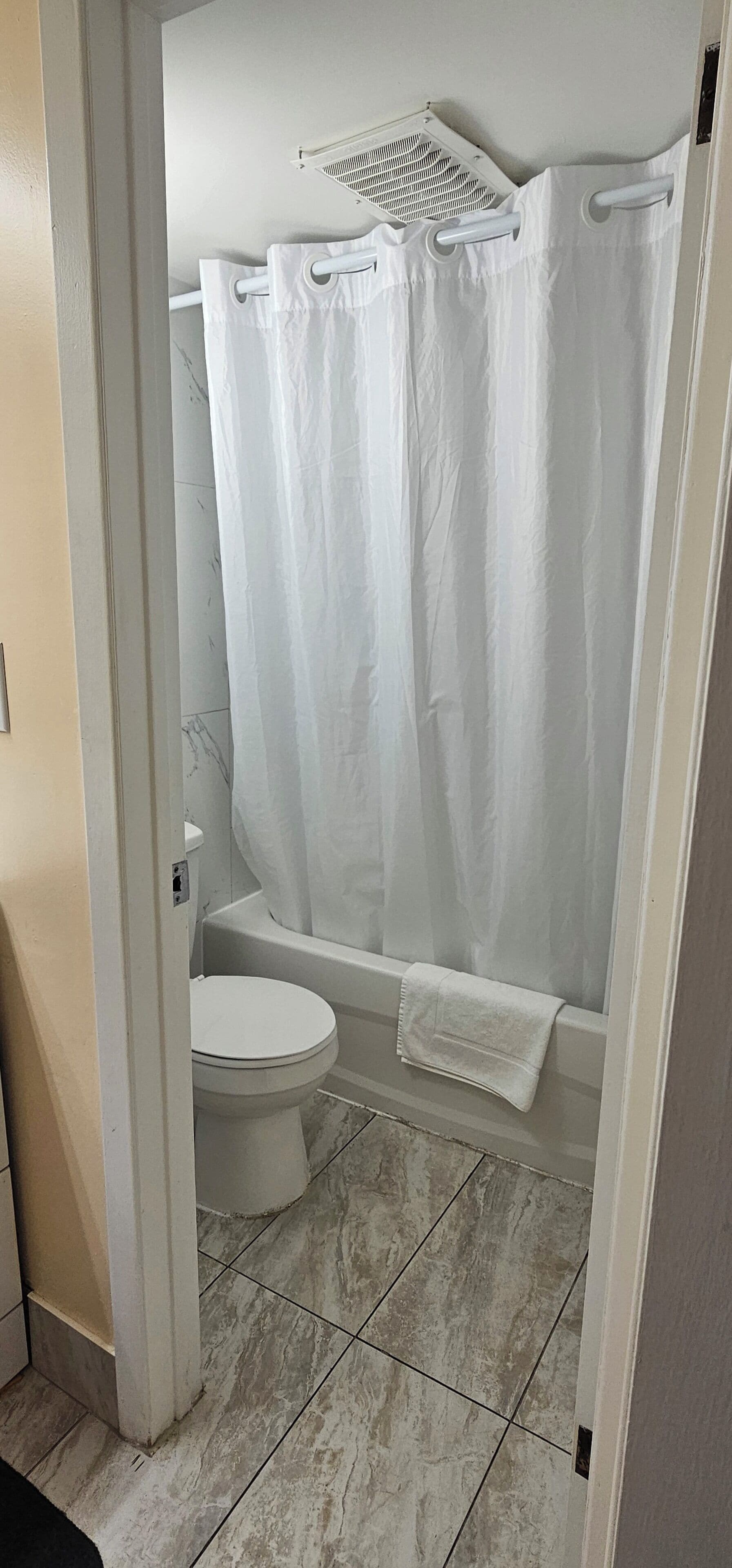 A bathroom with a white toilet, a bathtub, and a shower curtain.