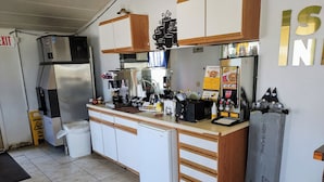 A compact kitchen with a coffee machine, a waffle maker, and a refrigerator.