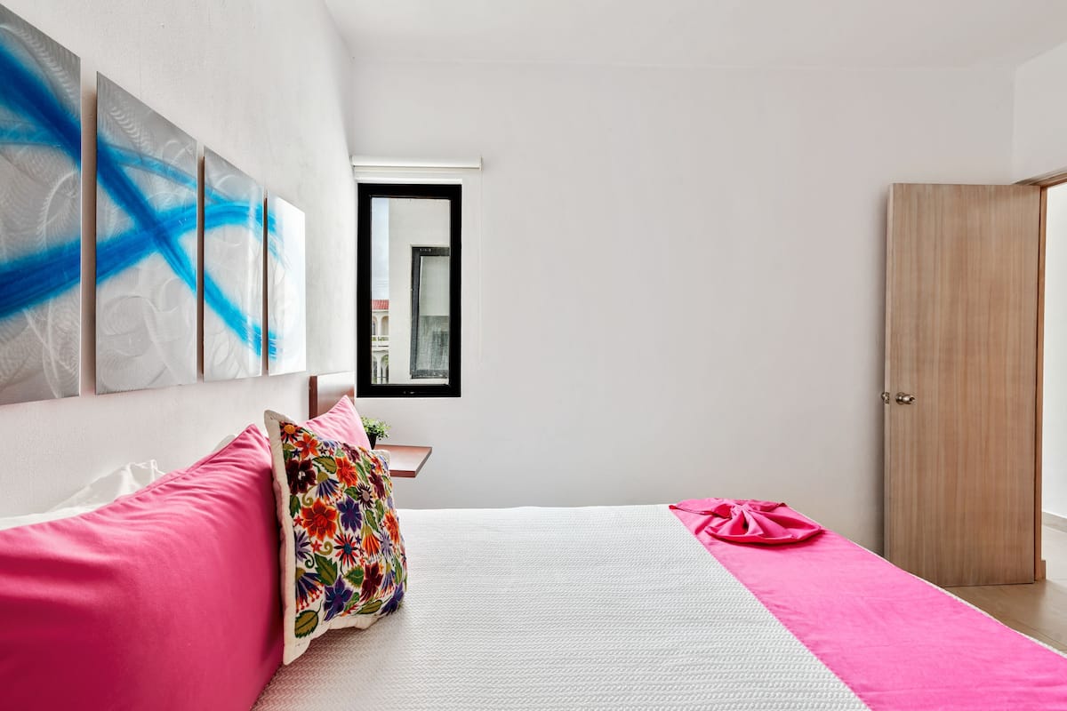 Un dormitorio moderno con cama, armario y arte abstracto en la pared.