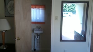 A bathroom with a sink, a mirror, and a door leading to a hallway. - Hiland Terrace Hotel (Irwin)