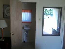 A bathroom with a sink, a mirror, and a door leading to a hallway.