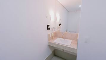 A modern bathroom with a white sink, a mirror, and a light fixture above the mirror.