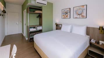 Una habitación de hotel con cama, armario, escritorio y mesita de noche.