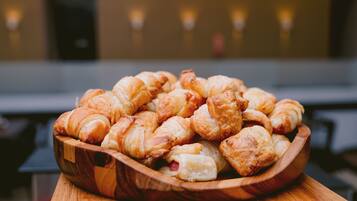 A wooden bowl filled with assorted pastries on a wooden table.
