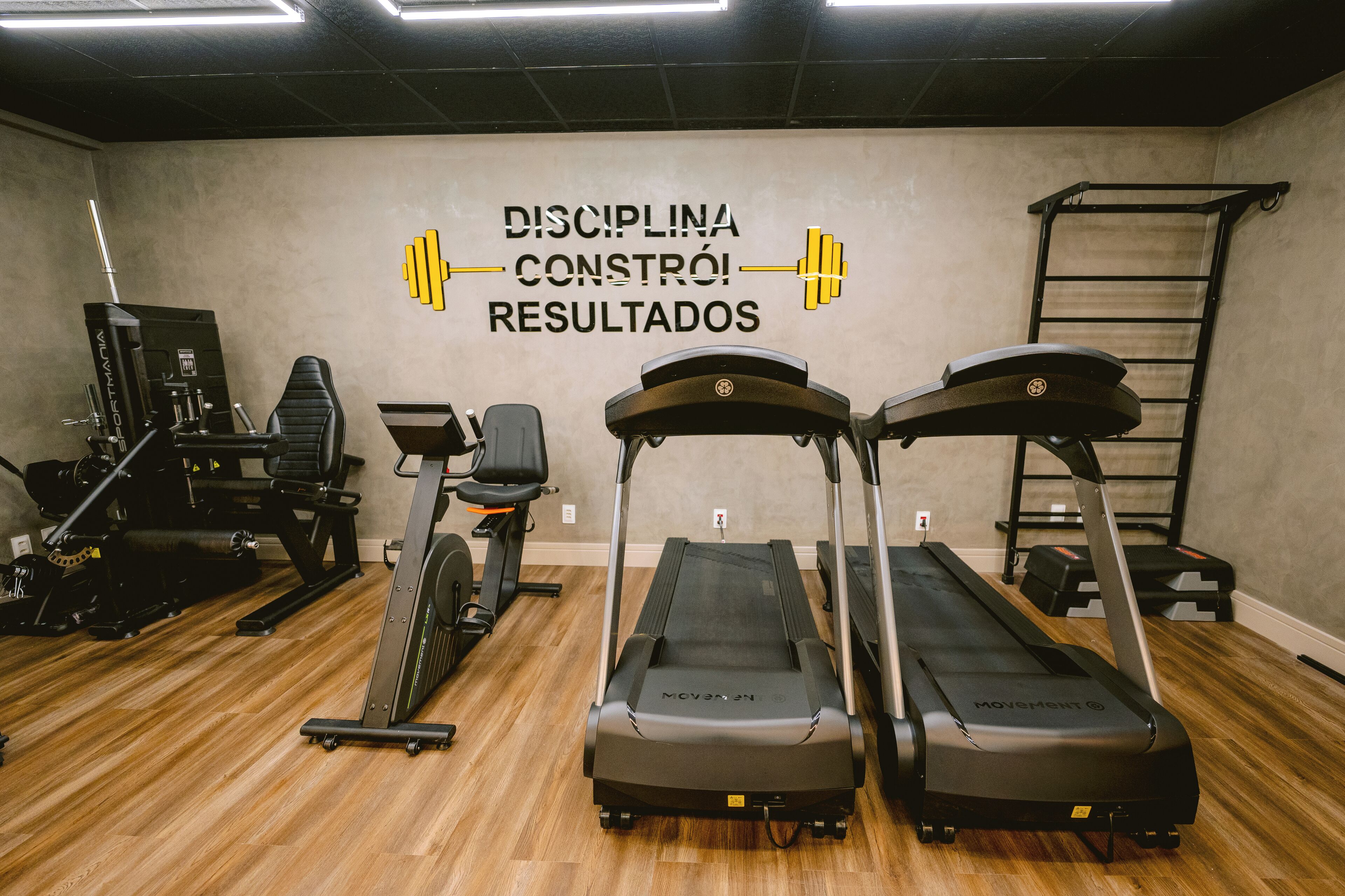 Een fitnessruimte met loopbanden, een bankdrukpers en krachttoestellen.