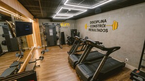 Un gimnasio con cintas de correr, máquinas de pesas y un televisor.