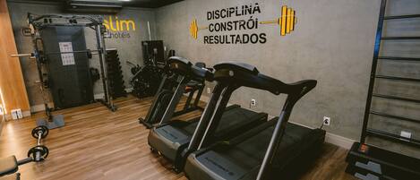 Un gimnasio con cintas de correr, máquinas de pesas y una pared con mensajes motivadores.