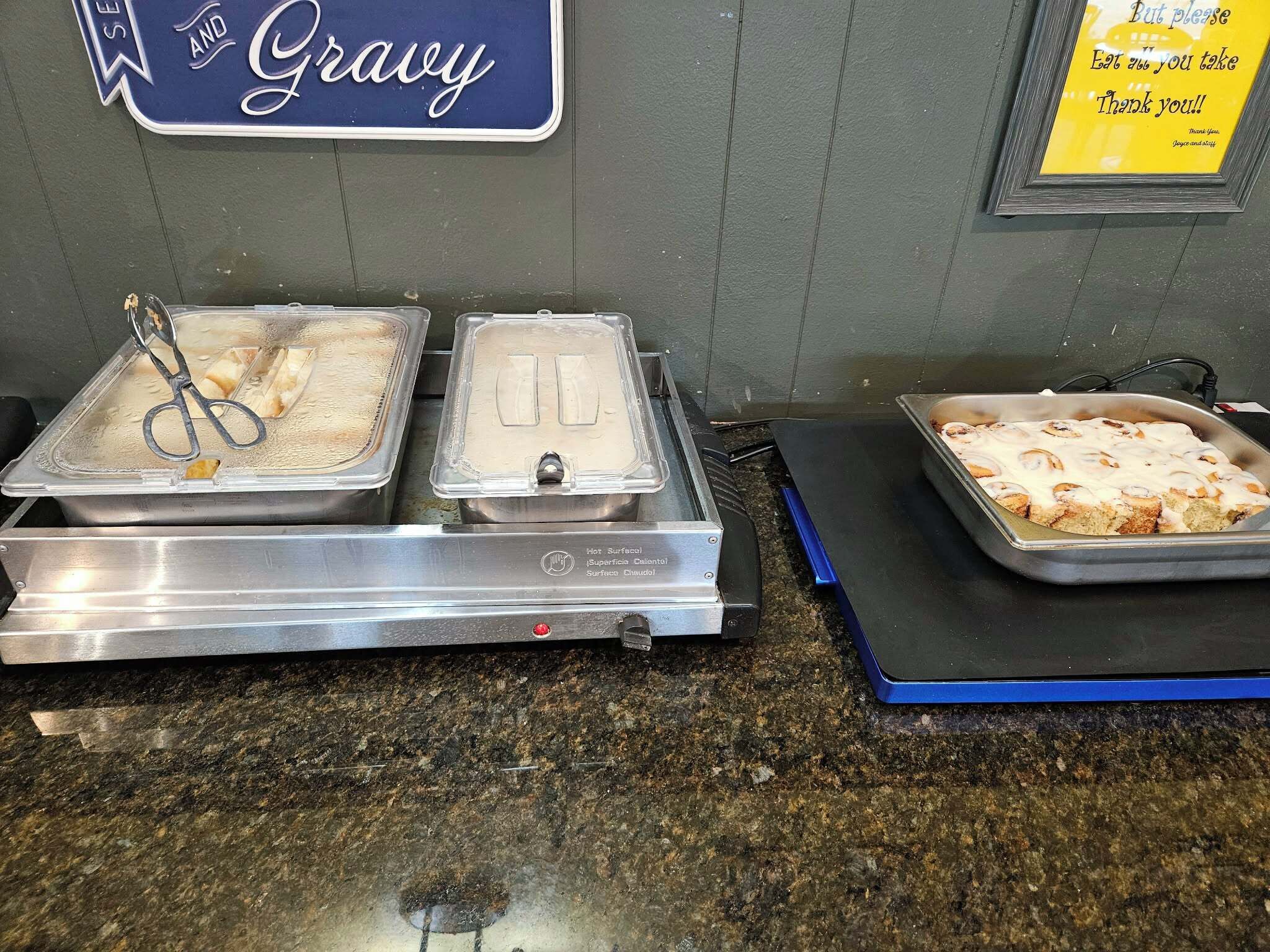 A buffet setup with hot food options, a sign indicating gravy, and a thank you note.