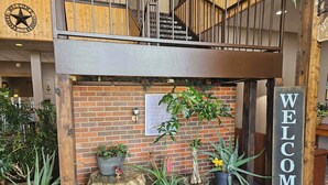 A reception area with a 'WELCOME' sign, a brick wall, potted plants, and a staircase. - The Lodge at Russell (Russell)