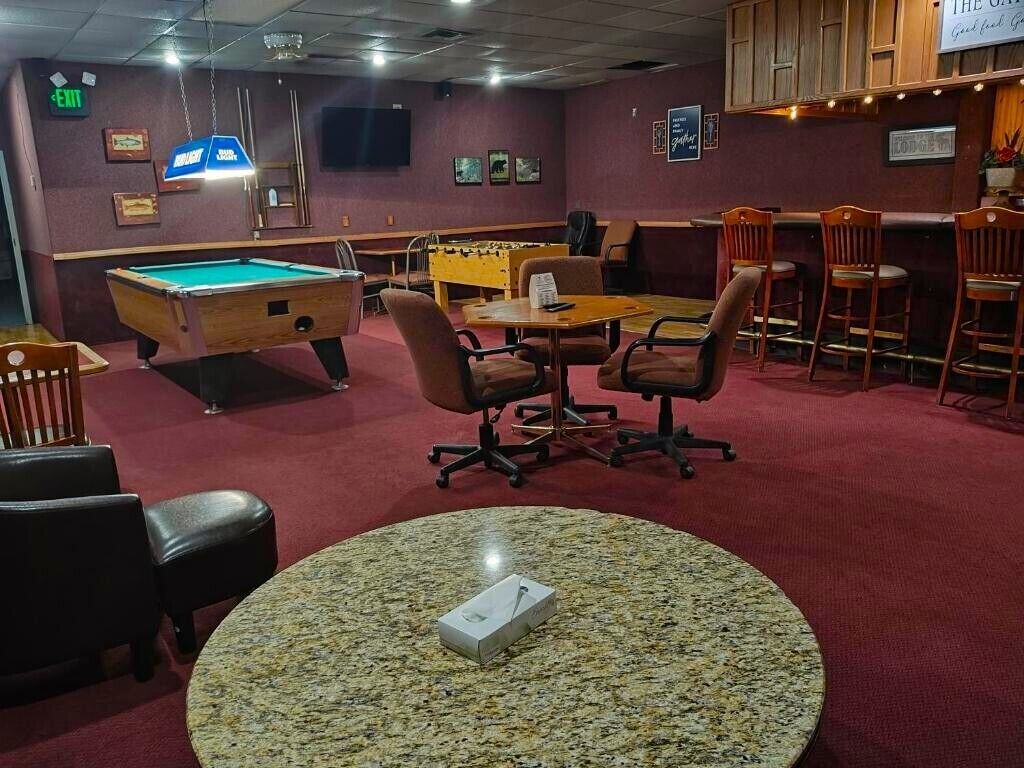 A billiards room with a pool table, chairs, and a foosball table.