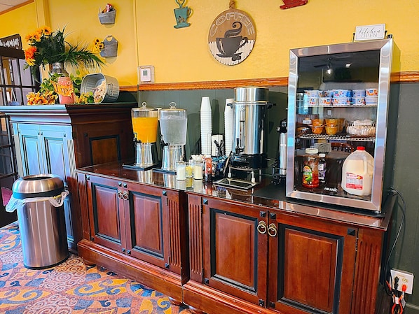 A bar area with a coffee machine, a milk dispenser, and a refrigerator stocked with beverages.