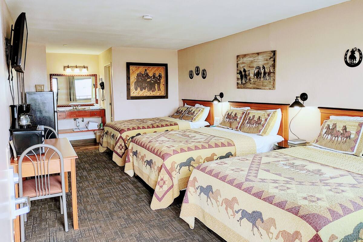 A hotel room with two beds, a desk, a chair, a television, and a mirror.