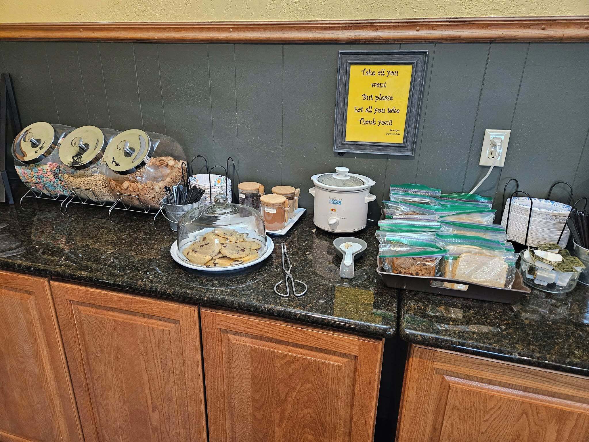 A buffet setup with various food items and a note on the wall.