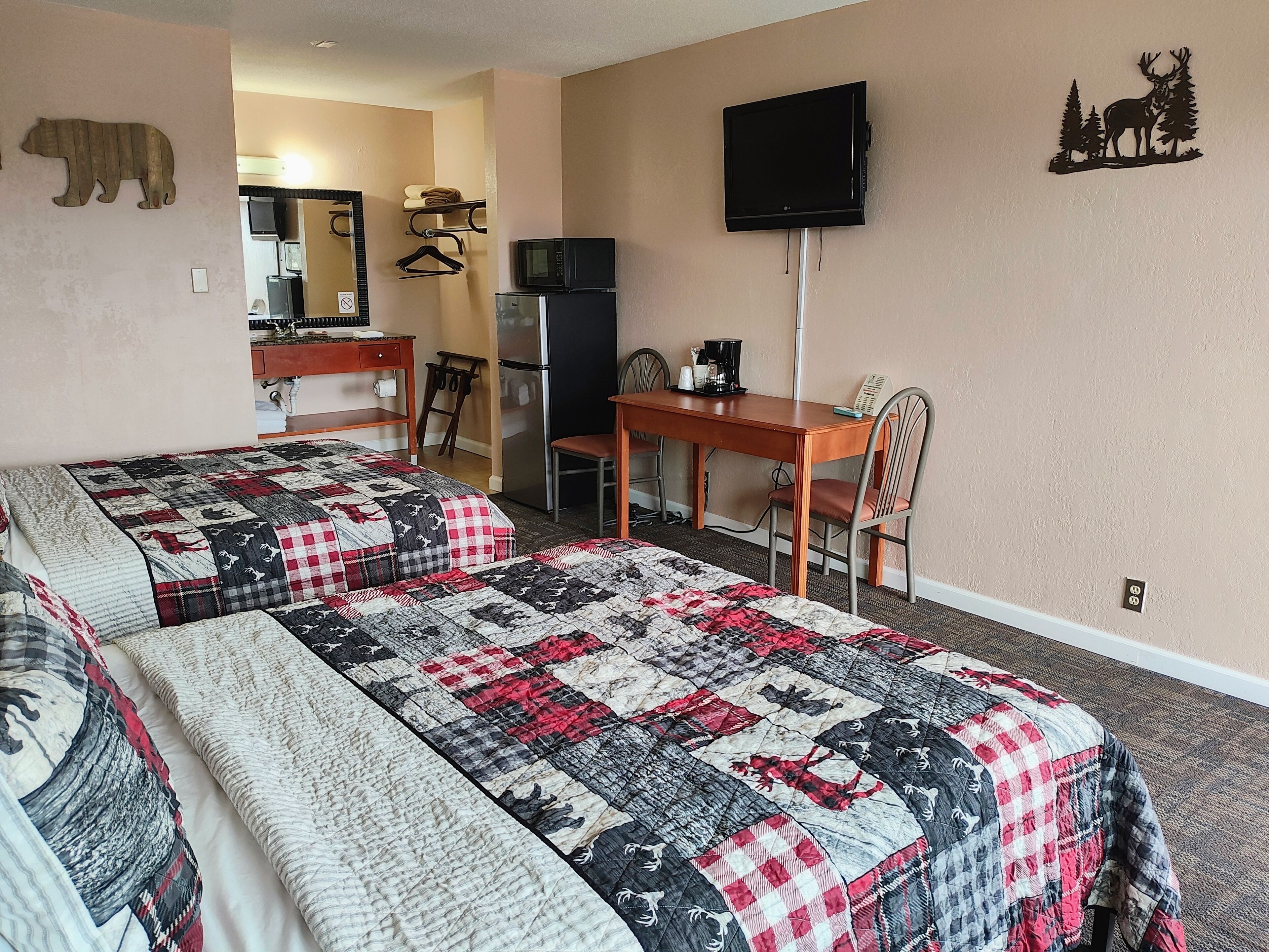 Habitación de hotel con dos camas, un escritorio, una silla, un televisor y un refrigerador.