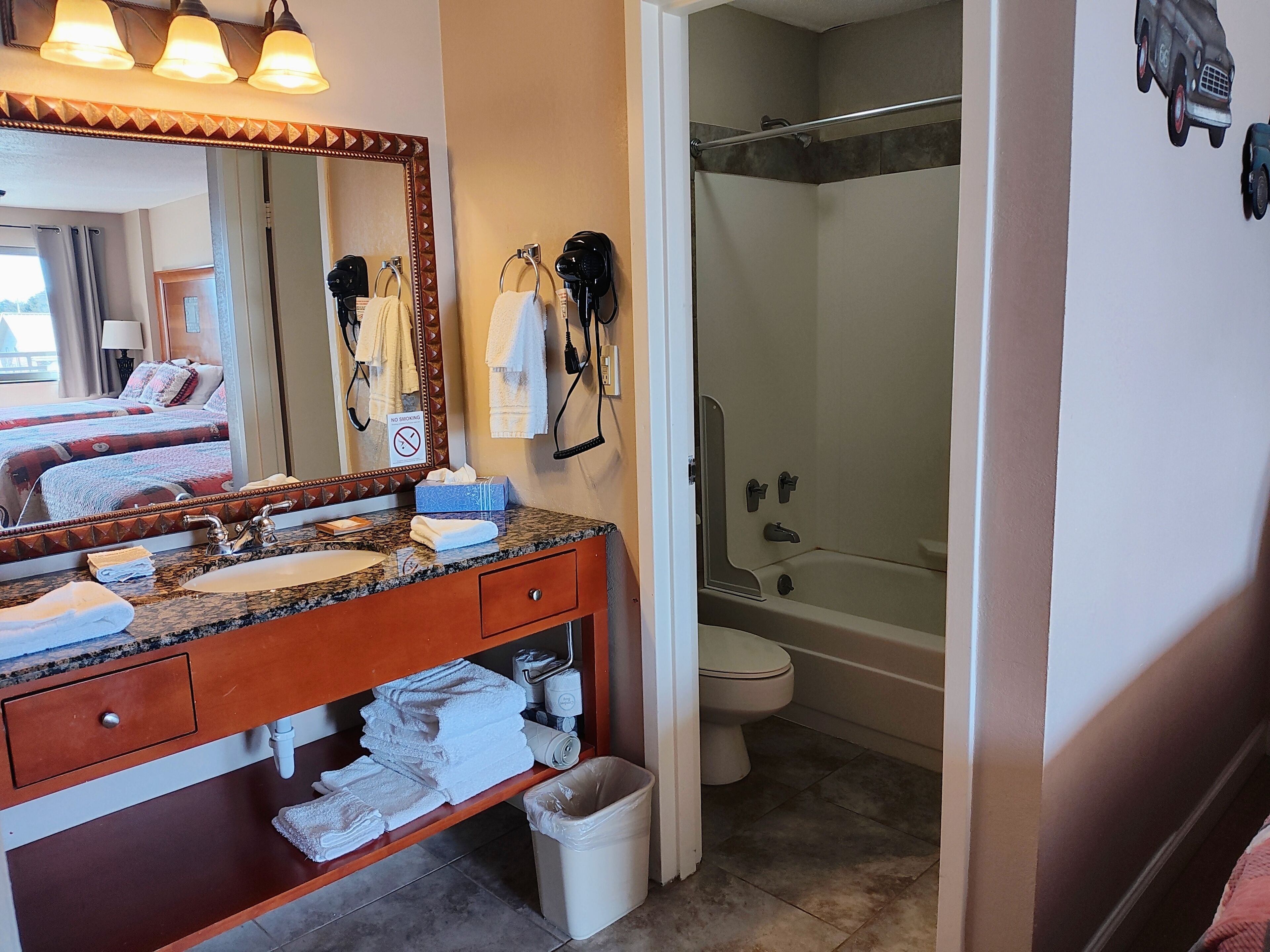 A bathroom with a vanity, sink, mirror, towel rack, and a shower area.