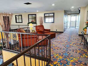 A hotel lobby with a patterned carpet, a brown leather sofa, and a railing.