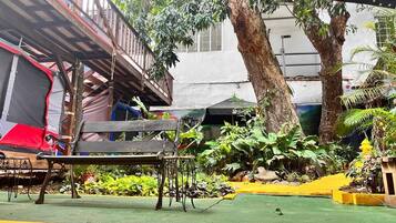 A courtyard with a wooden bench, a small table, and potted plants.