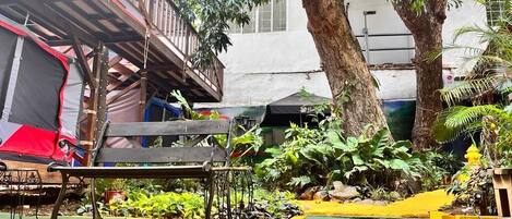 A courtyard with a wooden bench, a small table, and potted plants.