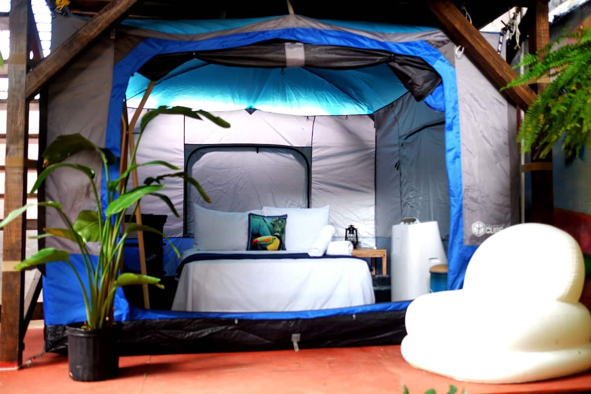 Een tent met een bed, een tafeltje en een bloempot.
