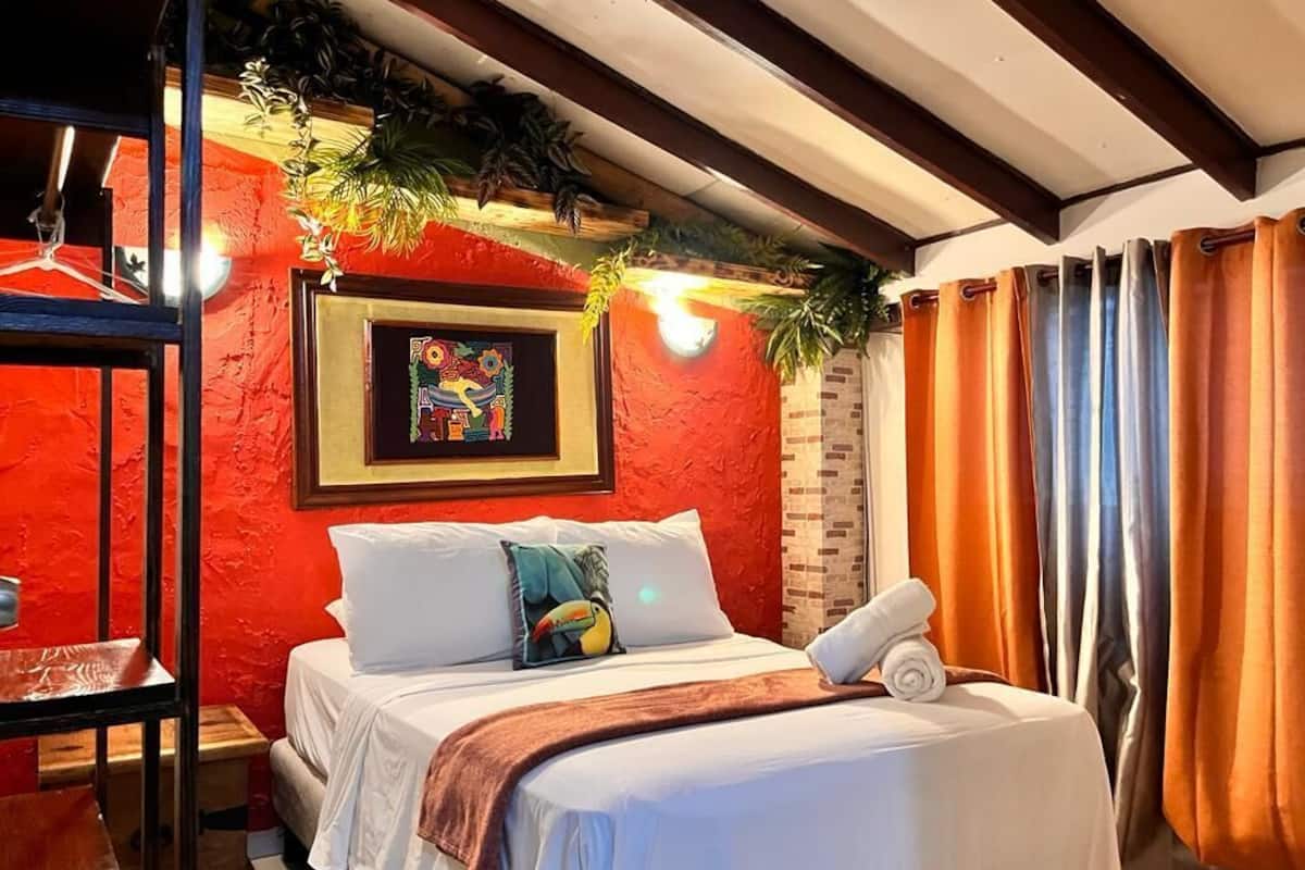 Een hotelkamer met een bed, een lijst met een foto aan de muur, en een raam met gordijnen.