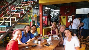 Un grupo de personas sentadas en una mesa de madera en un restaurante, con una escalera al fondo.