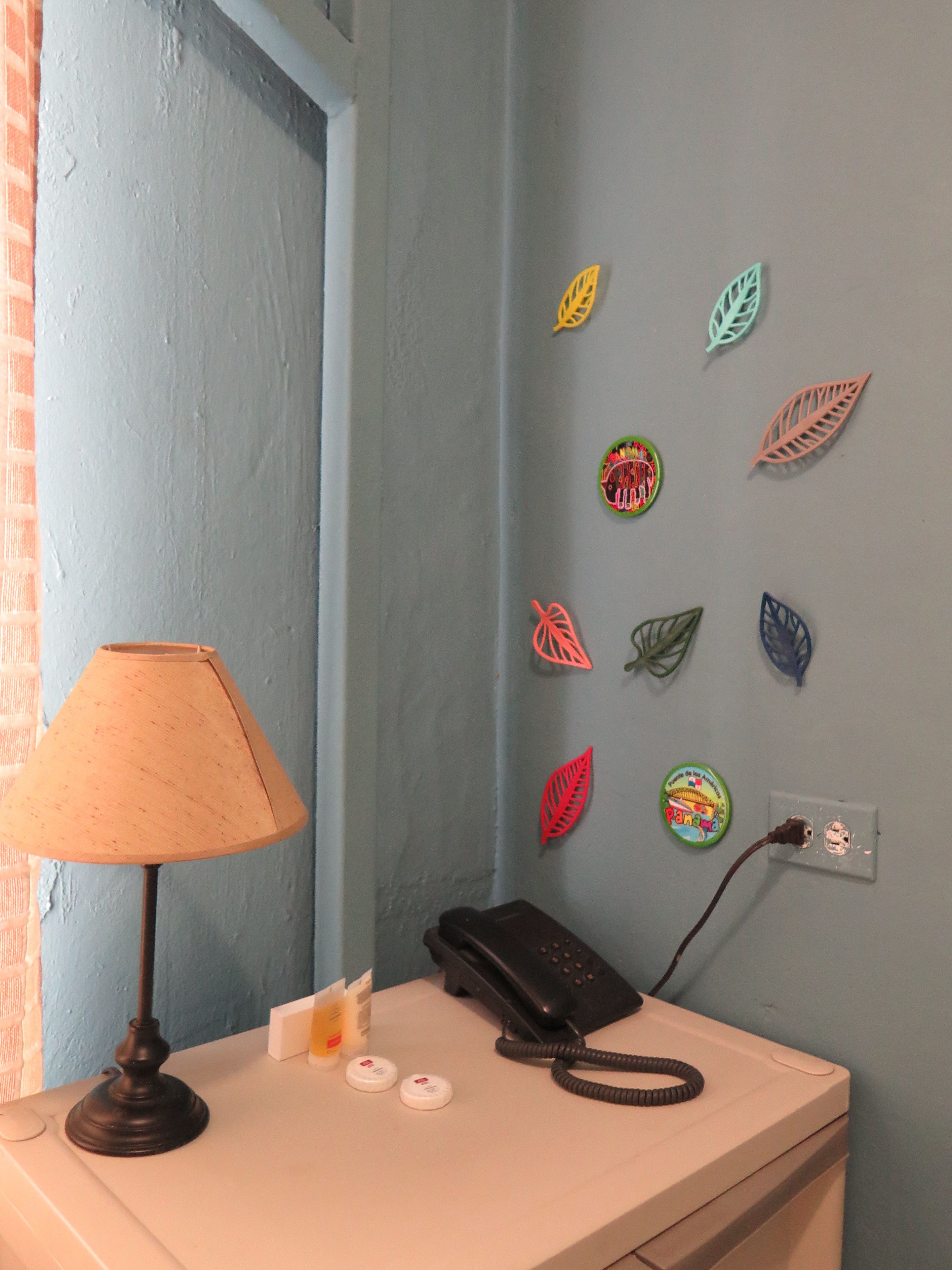 A room with a desk, a lamp, a phone, and wall decorations.