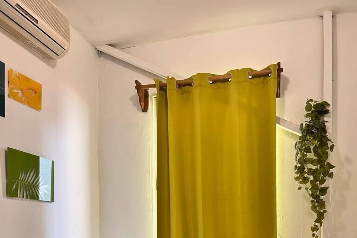 Een slaapkamer met een bed, een nachtkastje, een lamp en een potplant.