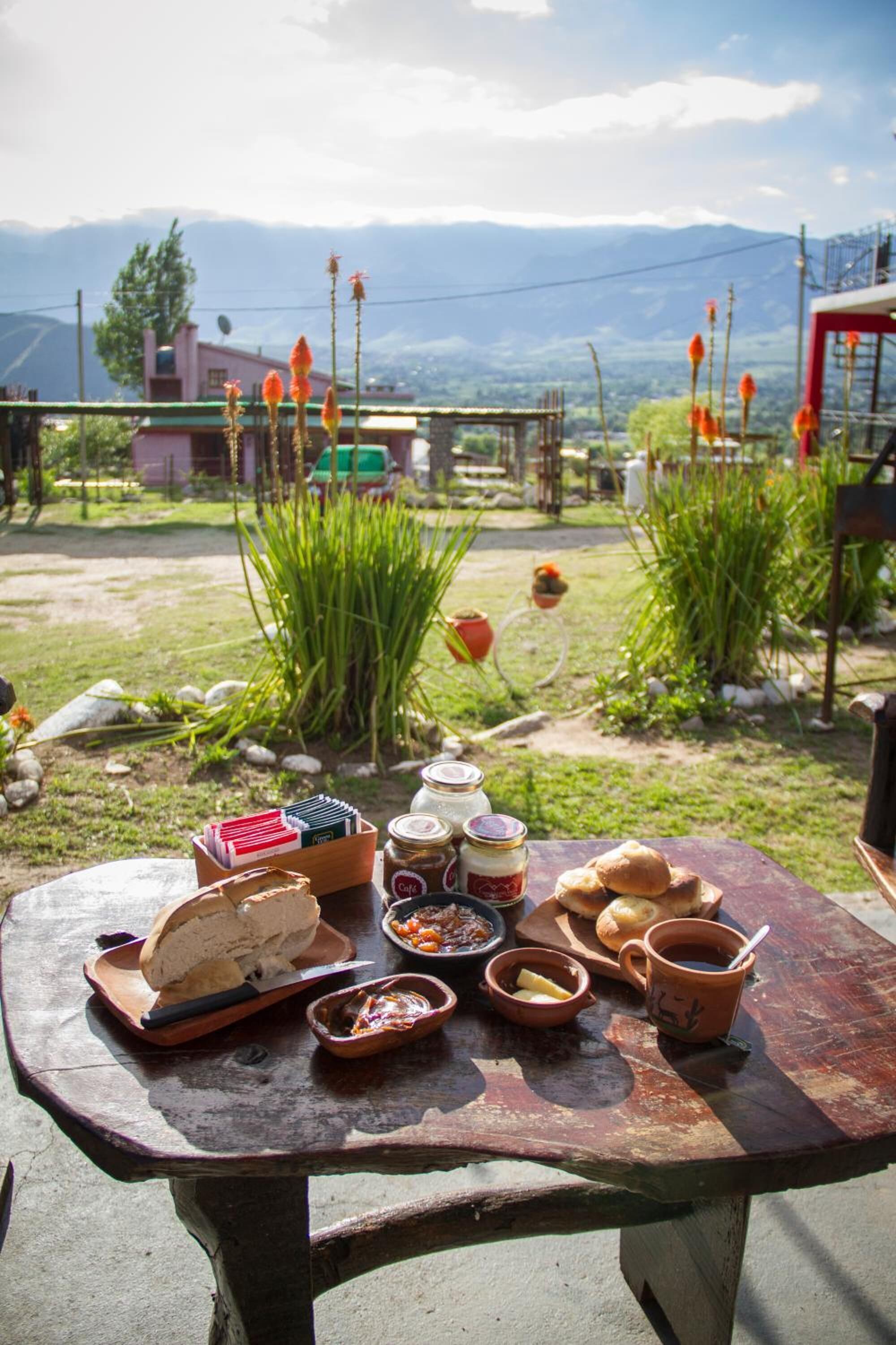 Een houten picknicktafel buiten, met eten en een uitzicht op bergen.