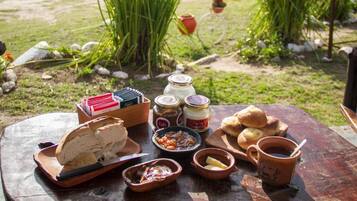 Een houten picknicktafel buiten, met eten en een uitzicht op bergen.