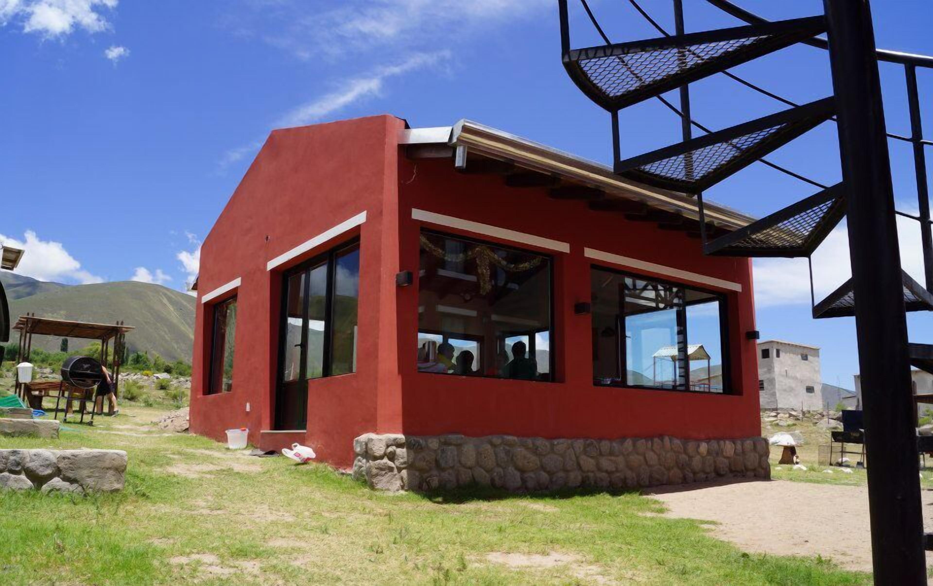 A red building with large windows and a stone foundation.