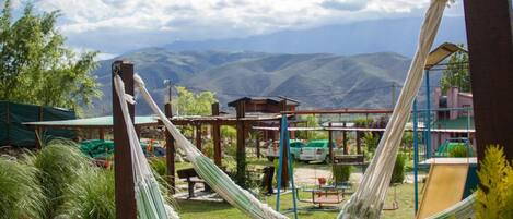 A hammock in a grassy area with mountains in the background.
