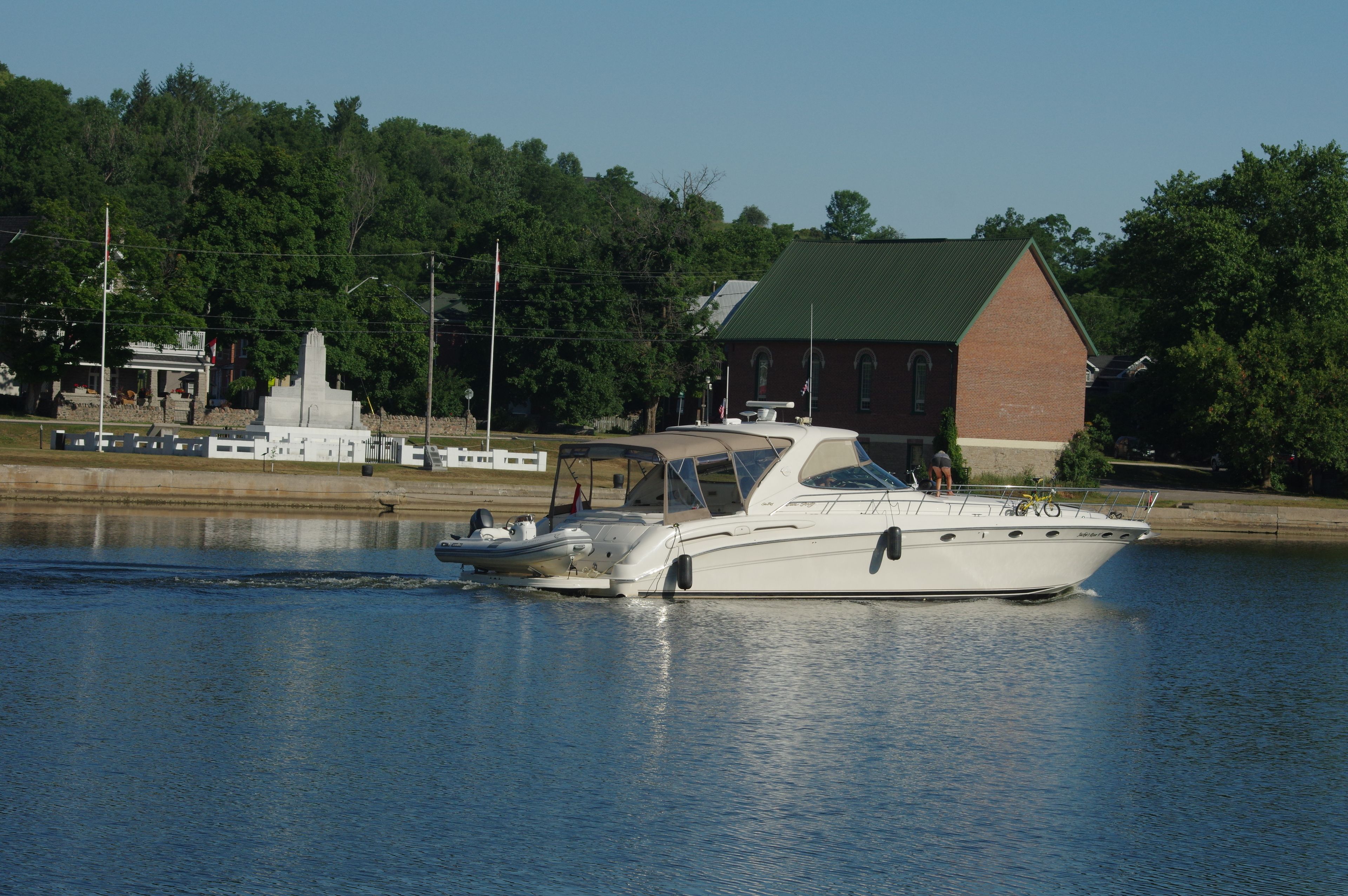 A white boat docked near a building with a green roof and a brick structure.