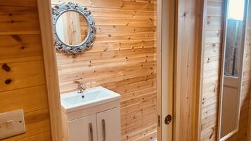 Un bagno con rivestimento in legno, un lavandino bianco, uno specchio e una porta.