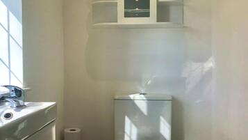 A compact bathroom with a toilet, a sink, and a cabinet above the toilet.