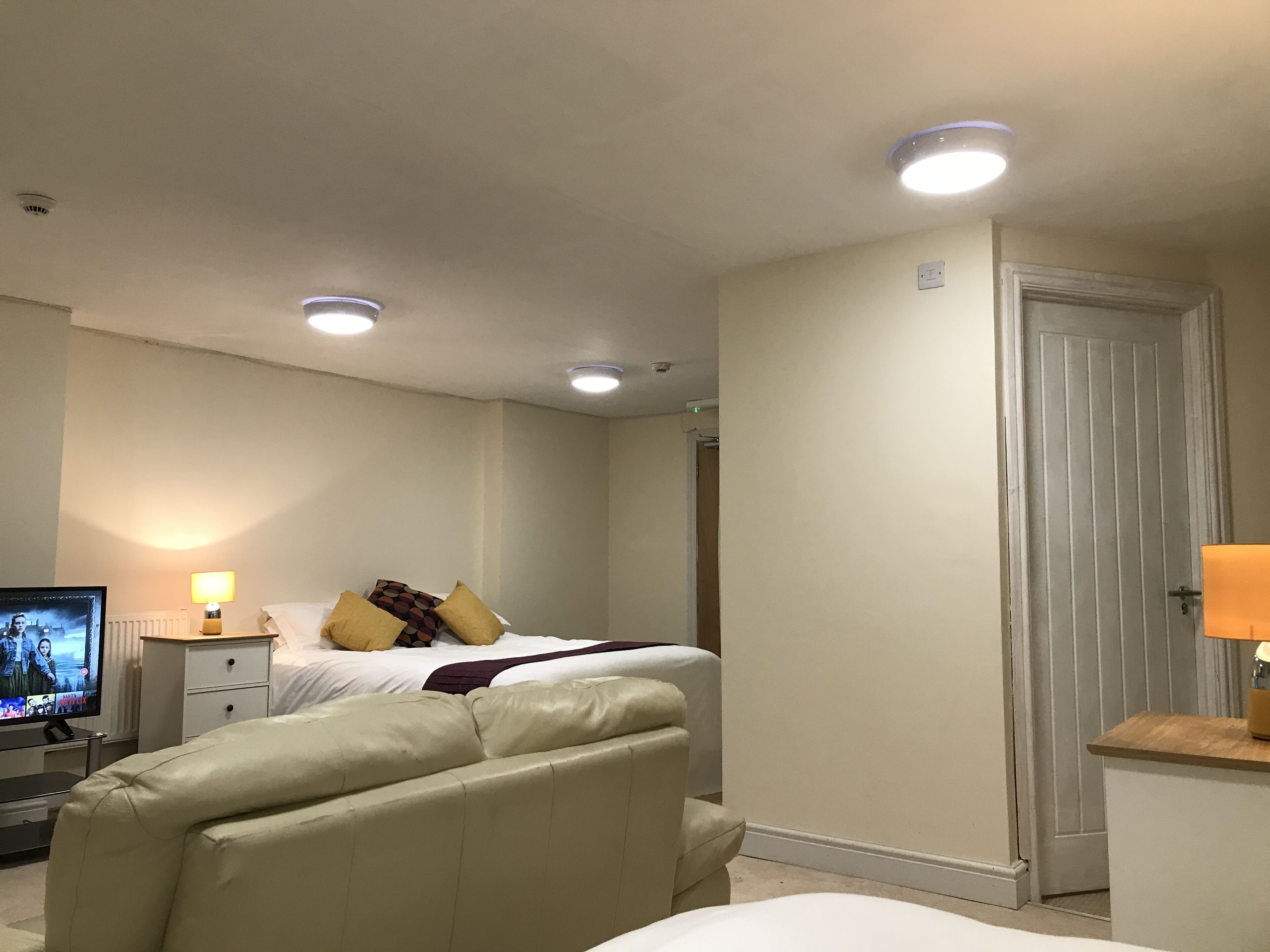 A hotel room with a bed, a TV, and a desk with a lamp.
