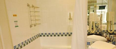 Une salle de bain avec une baignoire, un rideau de douche, un porte-serviettes et un lavabo avec un miroir.