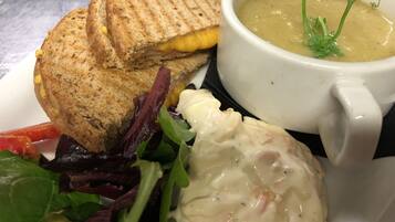 A sandwich with a side salad and a bowl of soup.