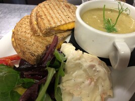 A sandwich with a side salad and a bowl of soup.