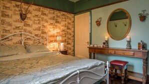 Een slaapkamer met een bed, een dressoir, een spiegel en een wand met dierenbehang.