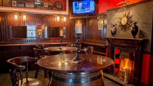 Een bar met houten meubels, een televisie en een open haard.