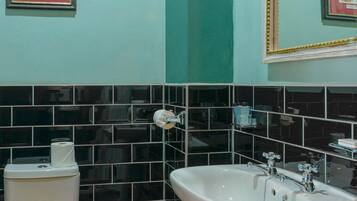 Un baño con inodoro, lavamanos y cubo de basura.