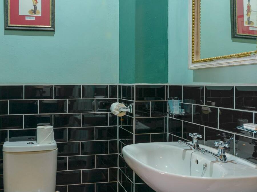 Un baño con inodoro, lavamanos y cubo de basura.