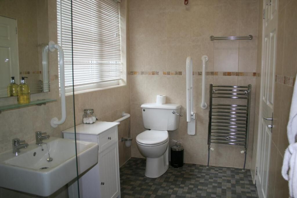 A bathroom with a toilet, sink, and glass shower enclosure.