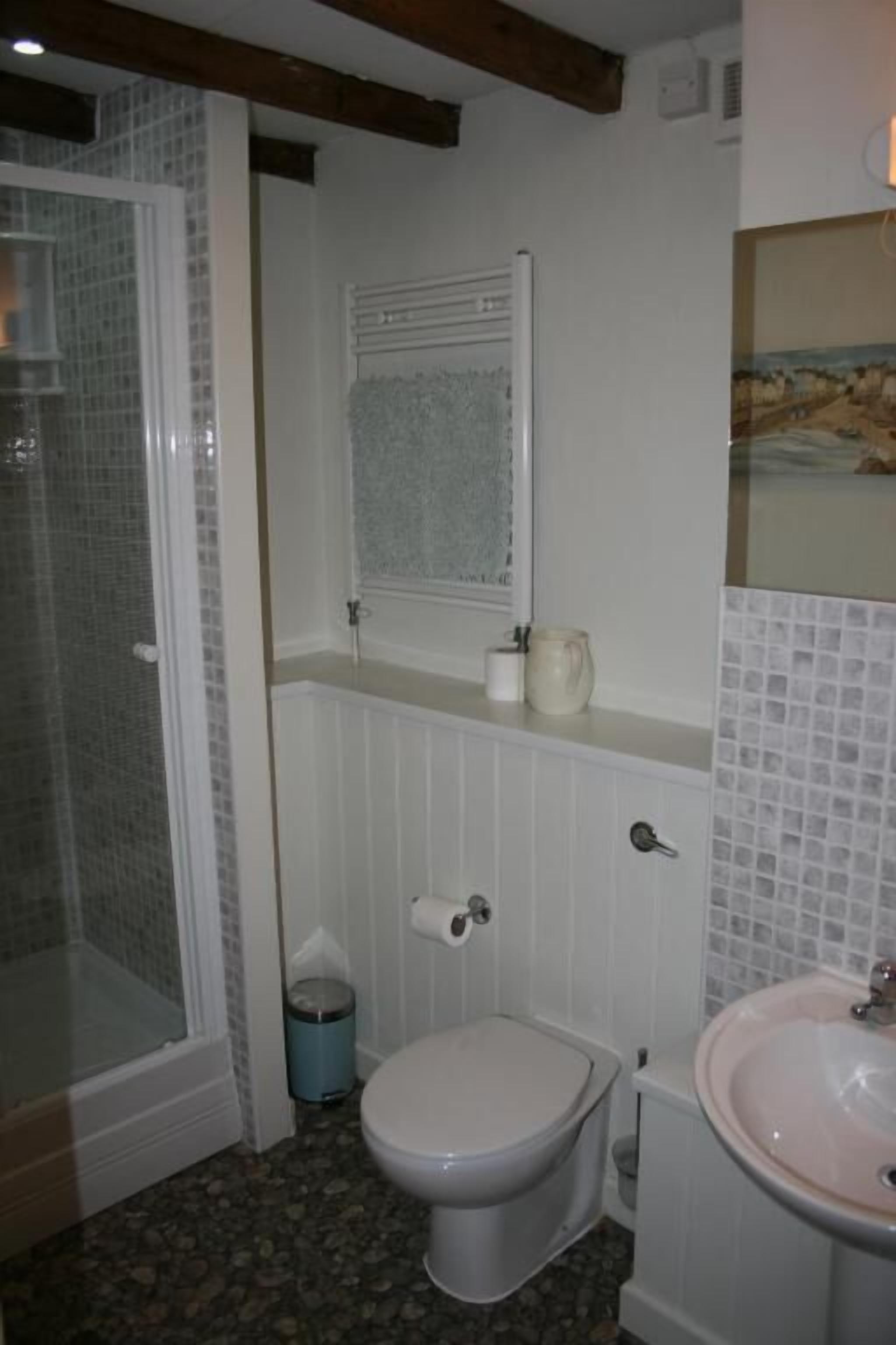 Et badeværelse med toilet, håndvask og bruseområde.