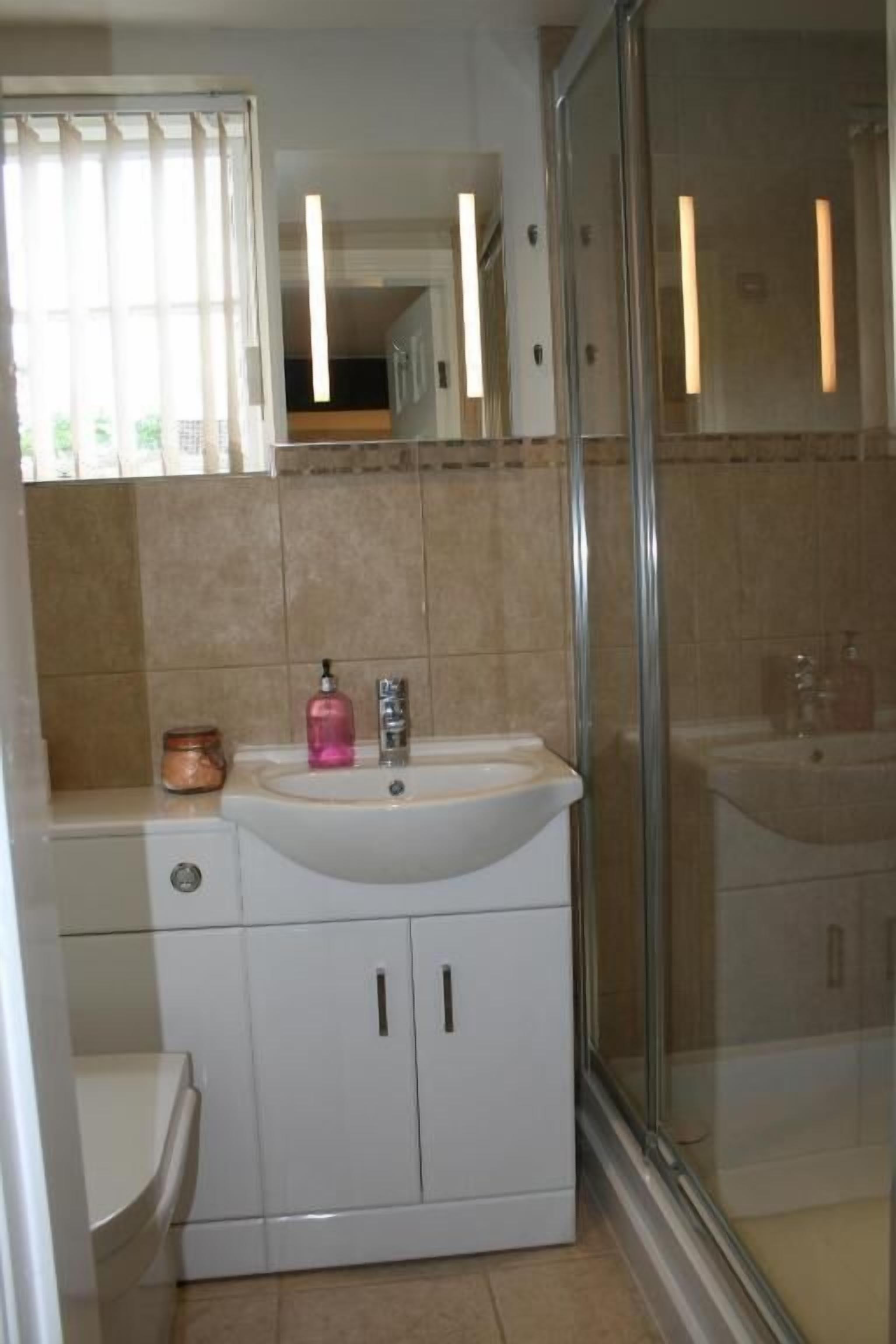 A bathroom with a white sink, a mirror, and a glass shower enclosure.