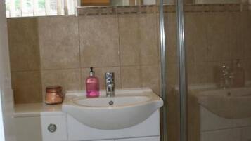 A bathroom with a white sink, a mirror, and a glass shower enclosure.